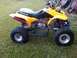 2006 Honda TRX 400 EX - Side view of a yellow ATV with a black seat and red exhaust pipe.