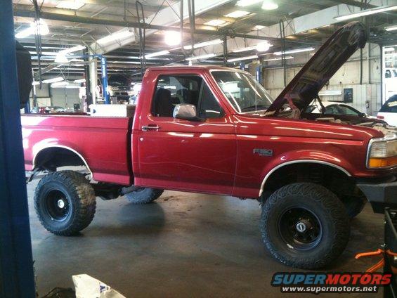 Red 1996 Ford F-150 with hood open in a garage