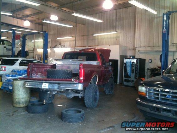 1996 Ford F-150 pickup truck in a garage with hood up, spare tire in bed