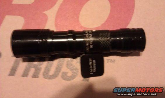 Black flashlight with text on barrel and a tag that says "1 AA BATTERY INCLUDED"