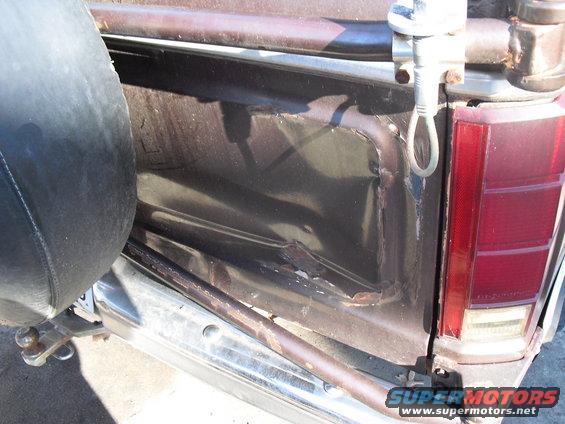 Spare tire mounted on the side, dented metal panel, and taillight on a truck