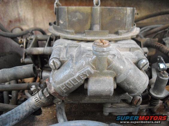 Close-up of a Holley carburetor with hoses attached. Some text is visible on the carburetor body