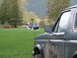 1990 Ford Bronco - A helicopter lands in a grassy field near a muddy green SUV.