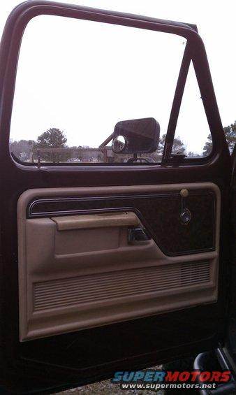 Brown and tan 1979 Ford Bronco interior door panel with chrome handle and woodgrain accent