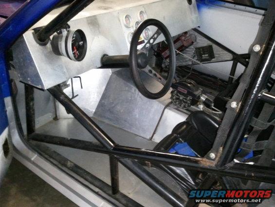 Custom race car interior with roll cage, racing seat, and dashboard gauges