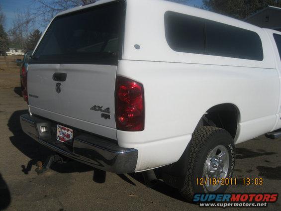 Rear view of a white pickup truck with a camper shell and 4x4 badging