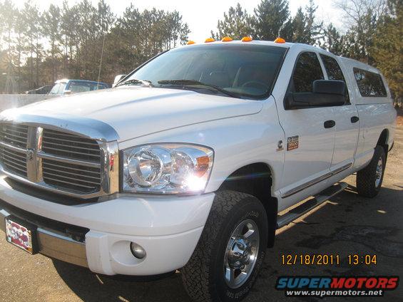 White Dodge Ram 3500 pickup truck with a cap, front 3/4 view