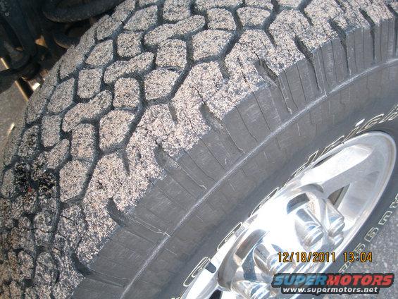 Tire covered in sand, showing tread pattern and chrome wheel. Date stamp 12/18/2011