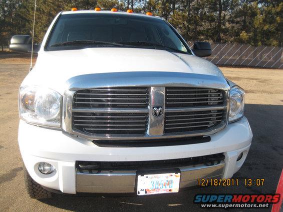 Front view of a white Dodge Ram pickup truck with a chrome grille and a license plate reading 3B545