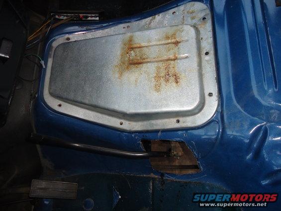 Blue truck cab interior with rusted metal panel and exposed floor