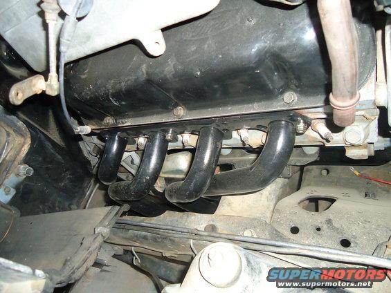 Close-up of exhaust manifold pipes bolted to an engine block