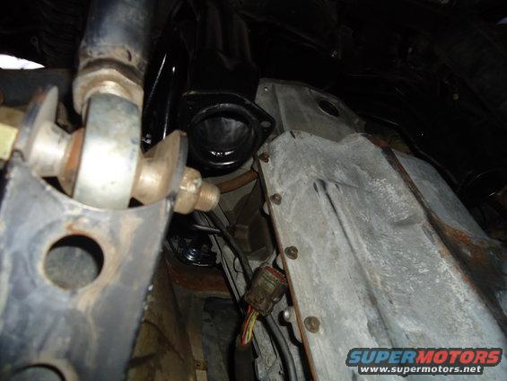 Close-up of exhaust manifold connection and suspension parts under a vehicle