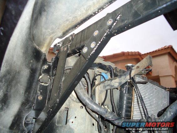 1987 Ford F-150 engine bay with radiator and black metal bracing. The area is dusty and shows signs of wear