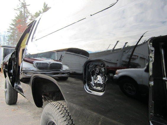 Black pickup truck side view, open door, reflection of International truck