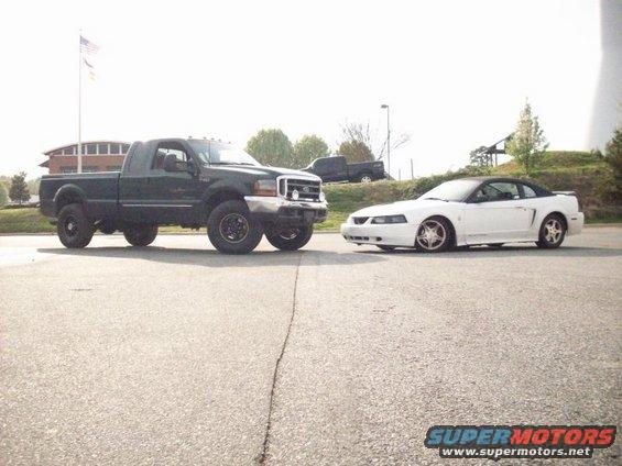 Green Ford F-250 truck parked next to a white Ford Mustang convertible