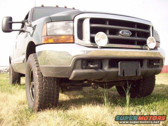 Front view of a dark green Ford Super Duty truck, possibly a 1999 model, with a chrome grille and large tires