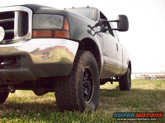 Dark green pickup truck, front quarter view, parked on grass. Chrome bumper, large side mirror