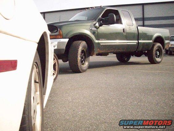 Green Ford F-350 pickup truck, 3/4 front view, parked on asphalt