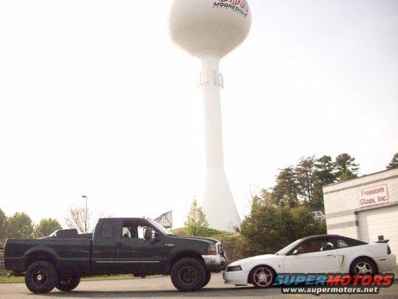 Side view of dark green Ford F-350 pickup truck next to a white Ford Mustang