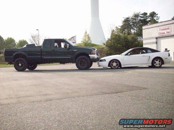 Dark green 2000 Ford F-350 Super Duty crew cab dually parked next to a white 2000 Ford Mustang GT convertible