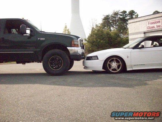 Green Ford F-350 truck bumper to bumper with white Ford Mustang
