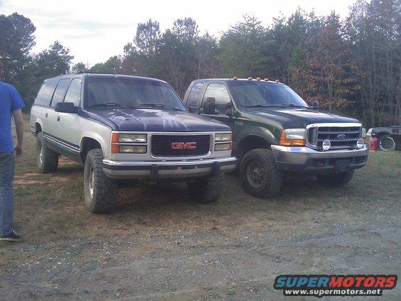 Green Ford F-Series truck parked next to a two-tone GMC Suburban