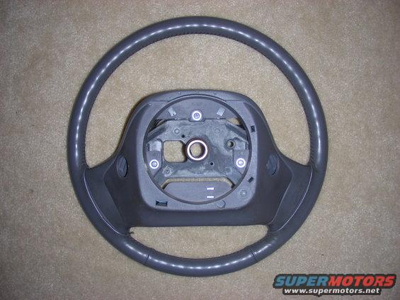 Gray steering wheel with dark gray plastic center hub, on a carpeted surface