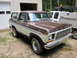 1969 Ford Mustang - This two-tone Ford Bronco is parked in front of a garage, with another truck visible behind it.