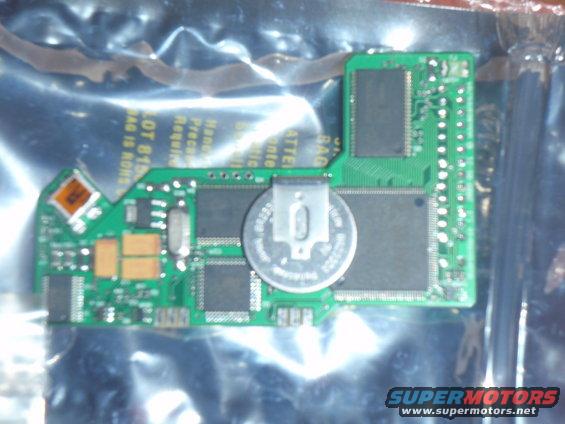 Circuit board with coin cell battery and chips, some text visible