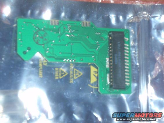 Green circuit board with black connector and warning symbols