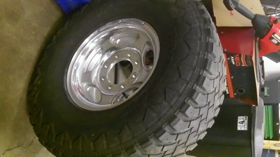 Tire and chrome wheel with five lug holes, angled view
