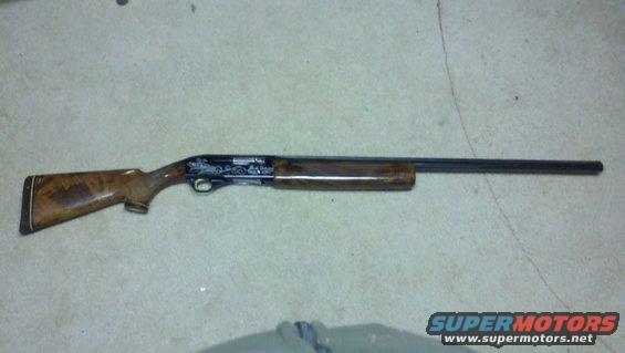 Shotgun with engraved receiver and wood stock on a concrete floor