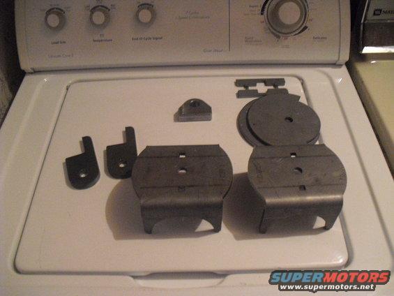 Several metal air suspension components laid out on a white washing machine lid