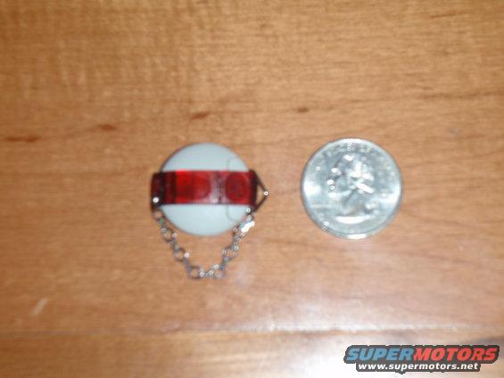 White reflector with red band and chain next to a US quarter