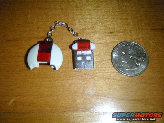 USB drive and white and red keychain fob next to a quarter on a wooden surface