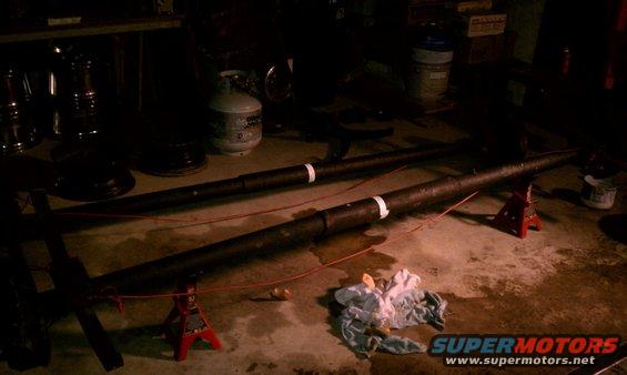 Two dark pipes supported by red jack stands in a dimly lit garage