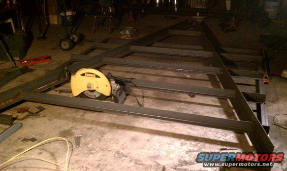 Metal frame construction with a yellow chop saw on a concrete floor