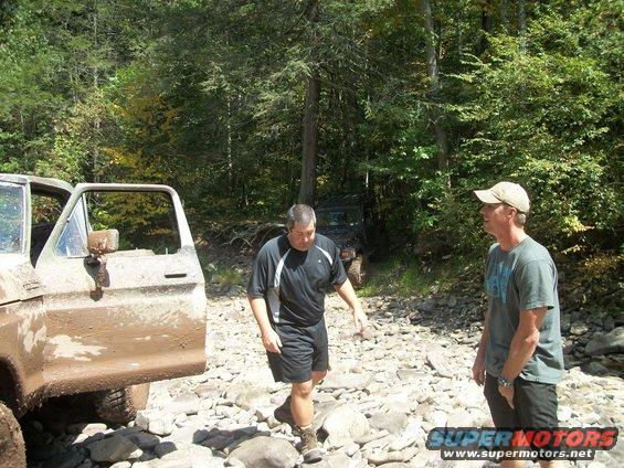 Muddy 1977 Ford F-150 with door open, and another off-road vehicle behind it. Two men stand on rocky ground