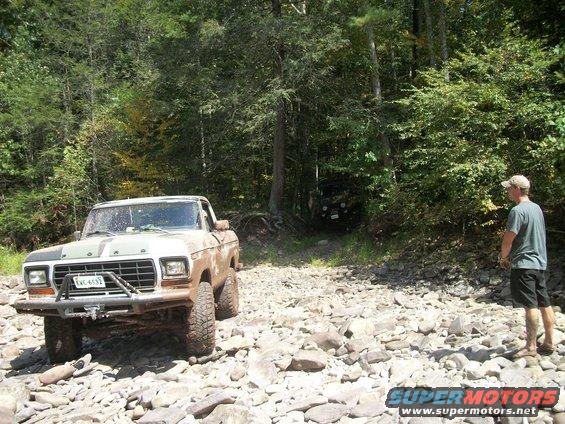 Mud-splattered 1979 Ford F-150 pickup truck with aftermarket bumper on rocky terrain