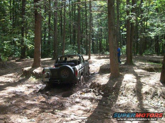 1979 Ford Bronco driving through mud in a forest