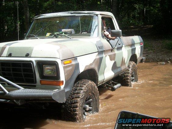 Ford F-Series pickup truck with camouflage paint driving through water
