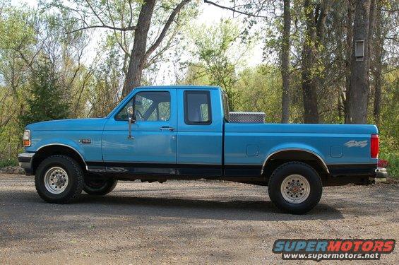 Blue 1992 Ford F-150 pickup truck, extended cab, parked on a dirt road with trees in the background
