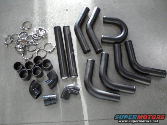 Collection of bent metal pipes and hose clamps on a concrete surface