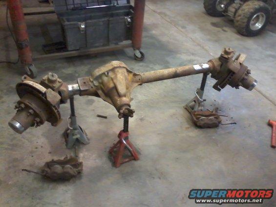 Front axle assembly on jack stands, showing differential, brake rotors, and calipers