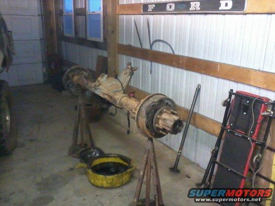 rear axle assembly on stands in garage, Ford sign on wall
