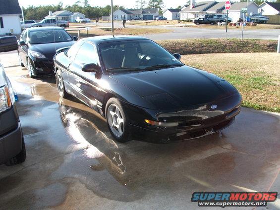Black 1994 Ford Probe parked on wet concrete, another car behind it