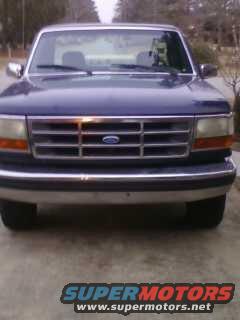 Blue Ford F-150 front grille with blue oval emblem. Headlights and bumper visible