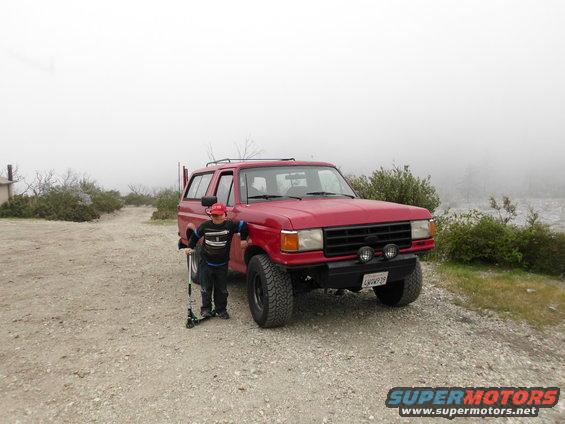 red SUV parked on dirt road with child next to it