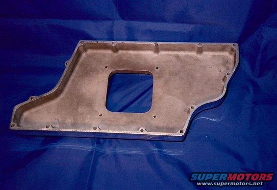 Aluminum oil pan with a square cutout and bolt holes, on a blue cloth background