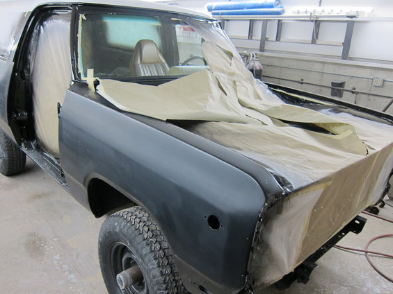 Truck in a workshop, covered in masking paper for paint prep. Door and fender are exposed